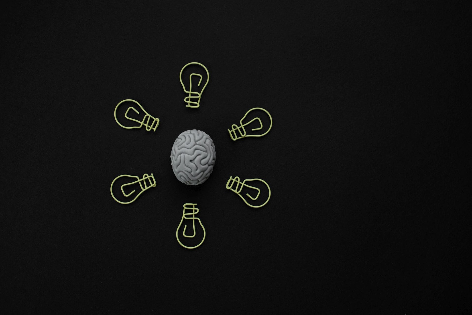 black and white. Brain in centre, encircled by lightbulbs.